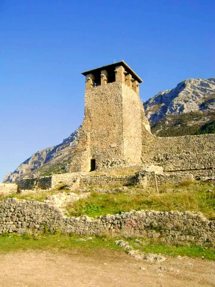 The stone tower and walls of Kruja castle below the mountain