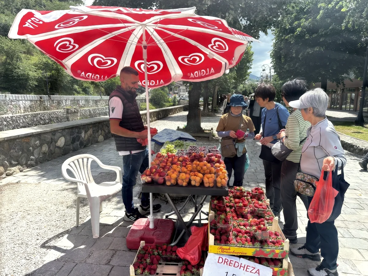 Travellers buying strawberries from a roadside fruit stall
