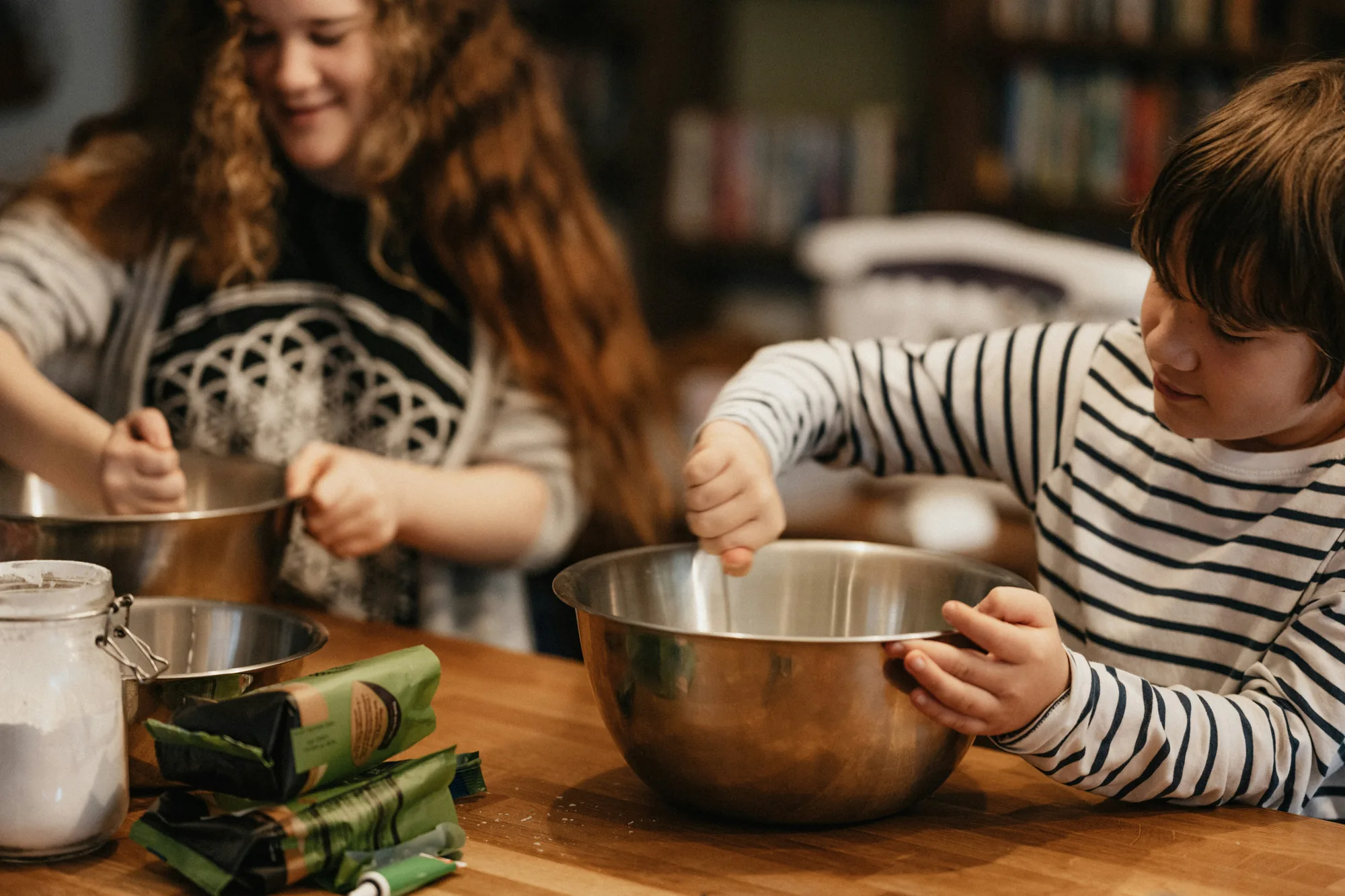 Two children mixing ingredients in bowls at a kitchen table