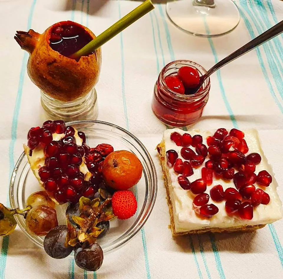 An Albanian dessert topped with pomegranate seeds beside fresh fruit