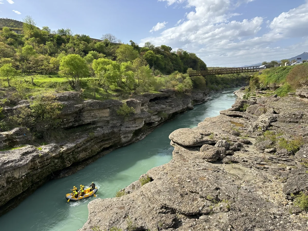 A raft on the turquoise Vjosa river between limestone banks