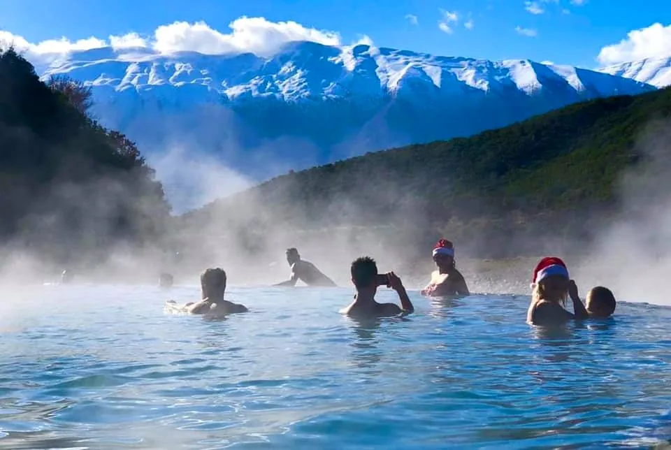A group of travellers bathing in the warm turquoise thermal pools at Bënja in summer