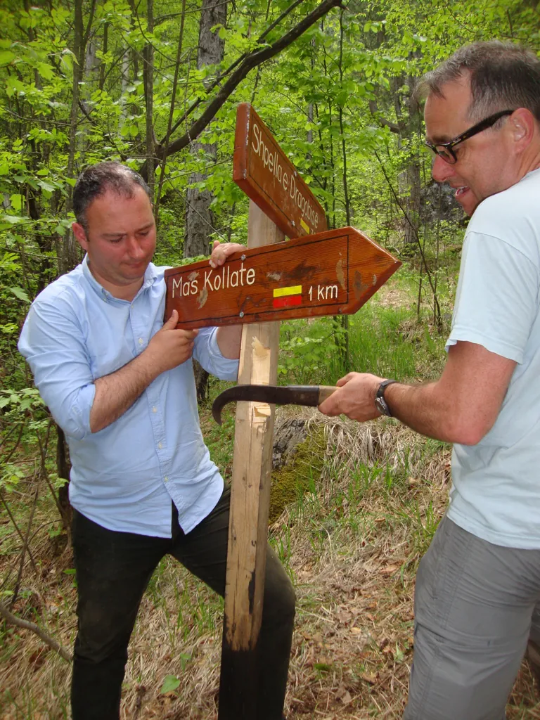 Two walkers reading a wooden trail sign