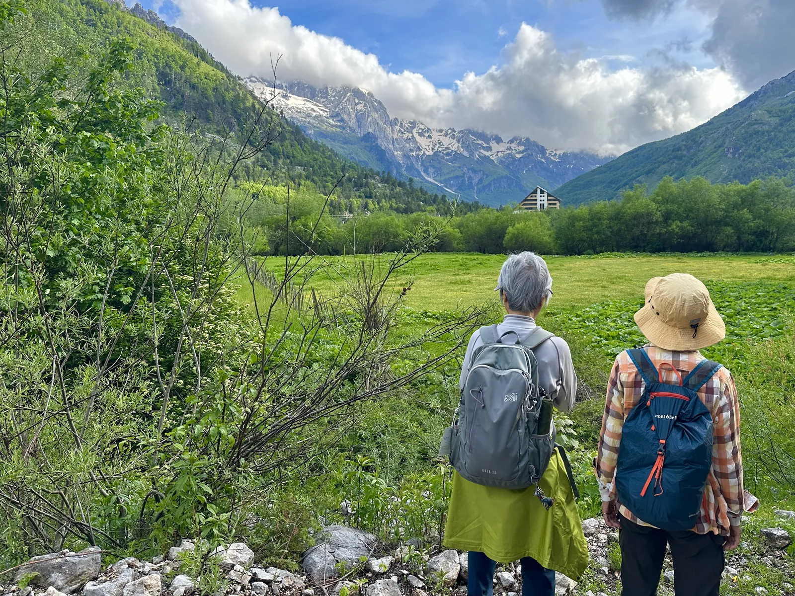 Two walkers pausing to look across a mountain valley