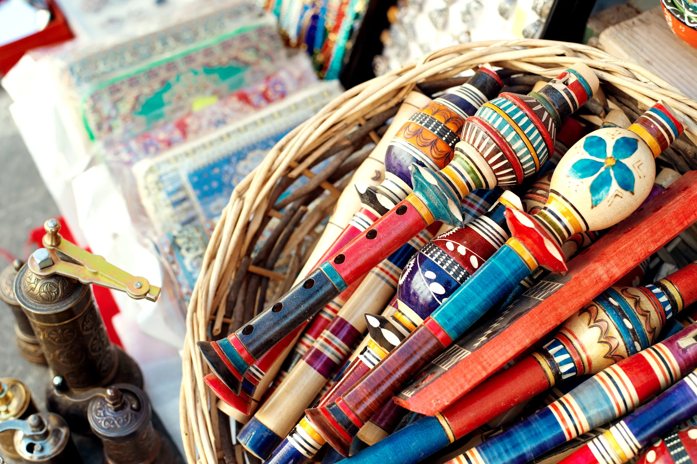 Hand-painted wooden flutes and woven rugs on a market stall in Albania