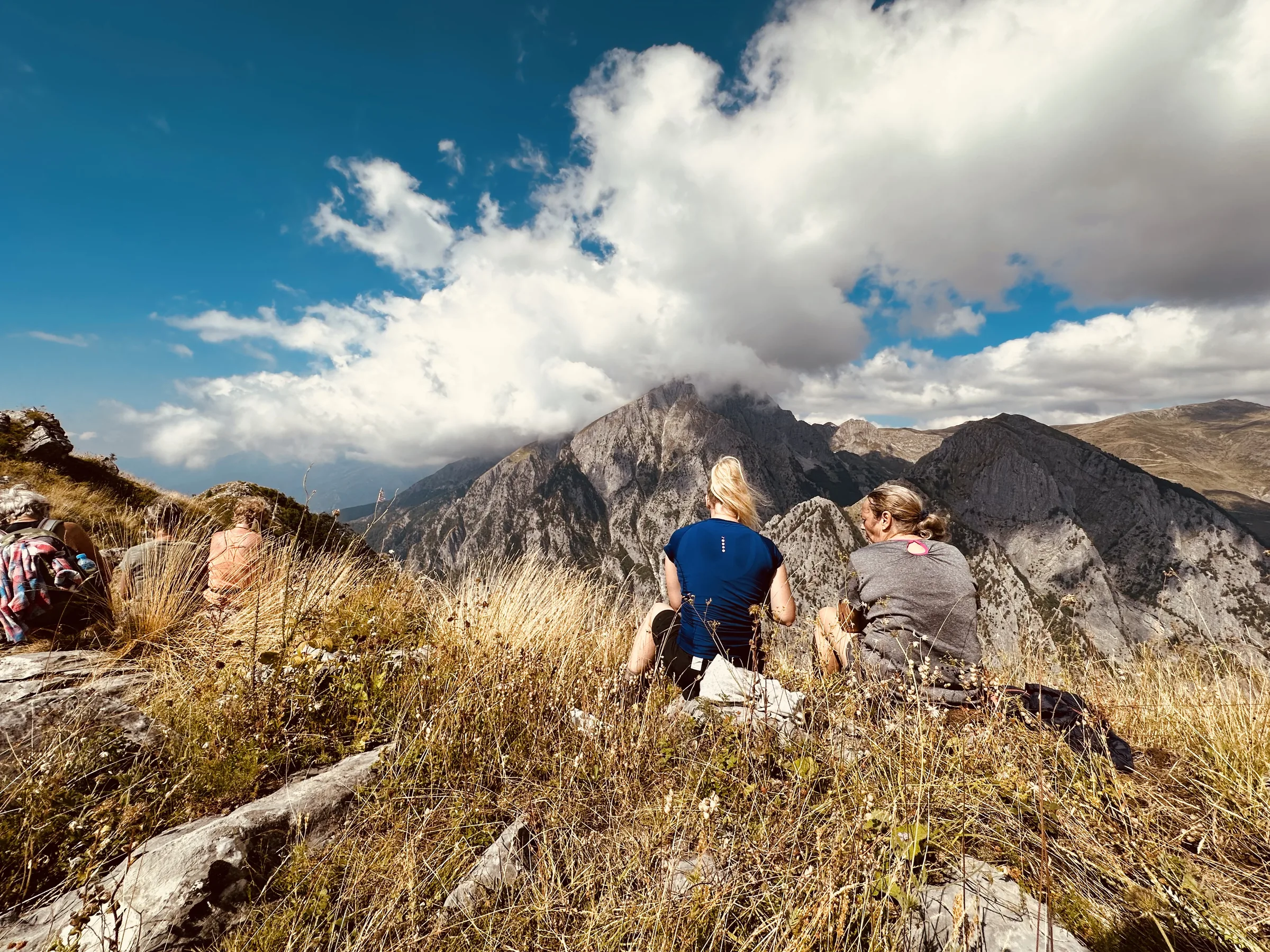 Walkers resting on a ridge with cloud breaking over the peaks