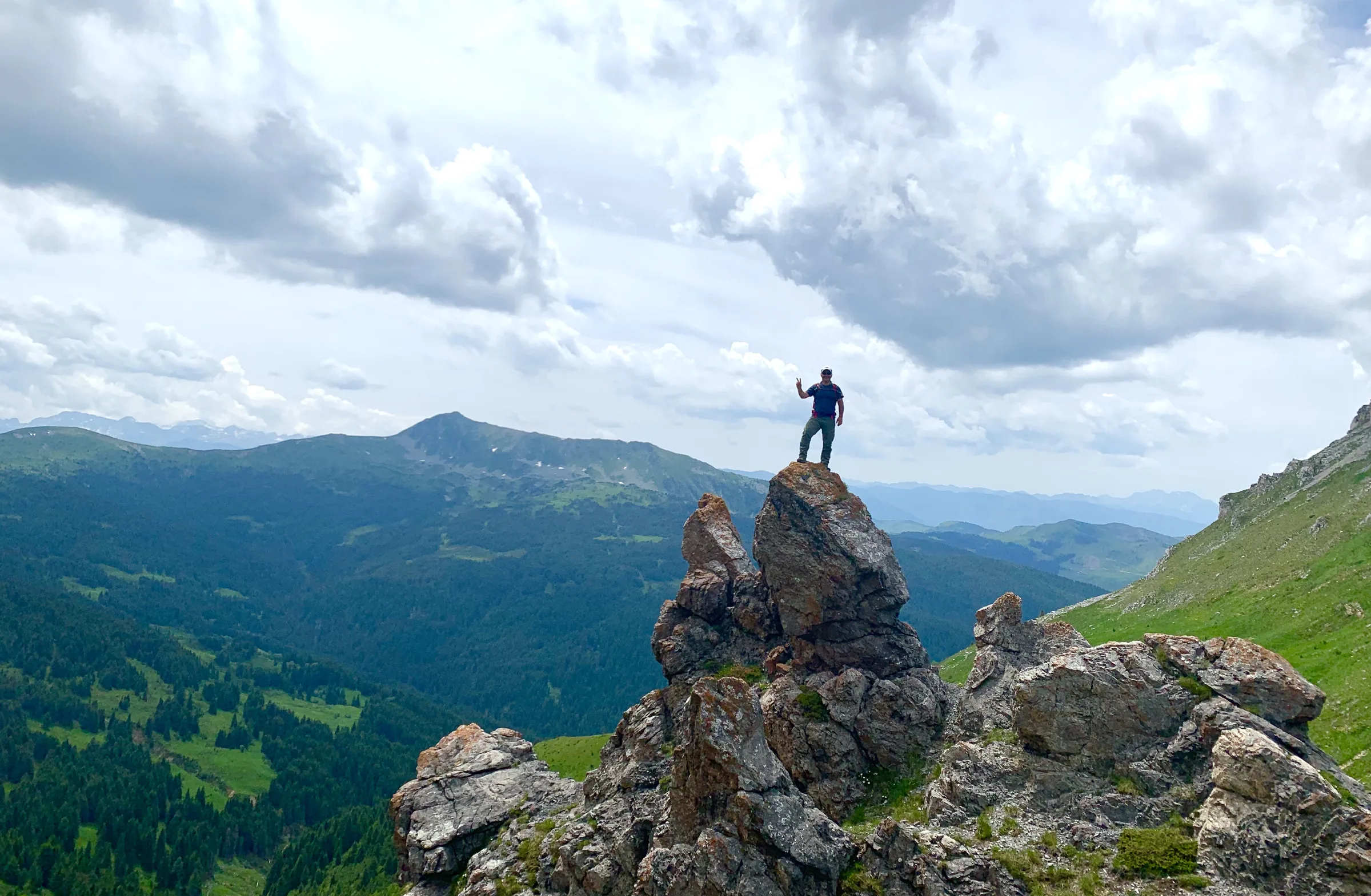 A walker on a rocky outcrop high above the summer pastures