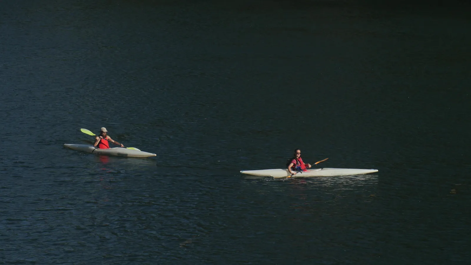 Two kayaks crossing still, dark water
